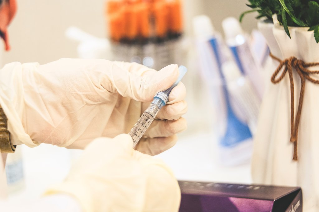 Mão manipulando uma seringa de remédio contra o HIV