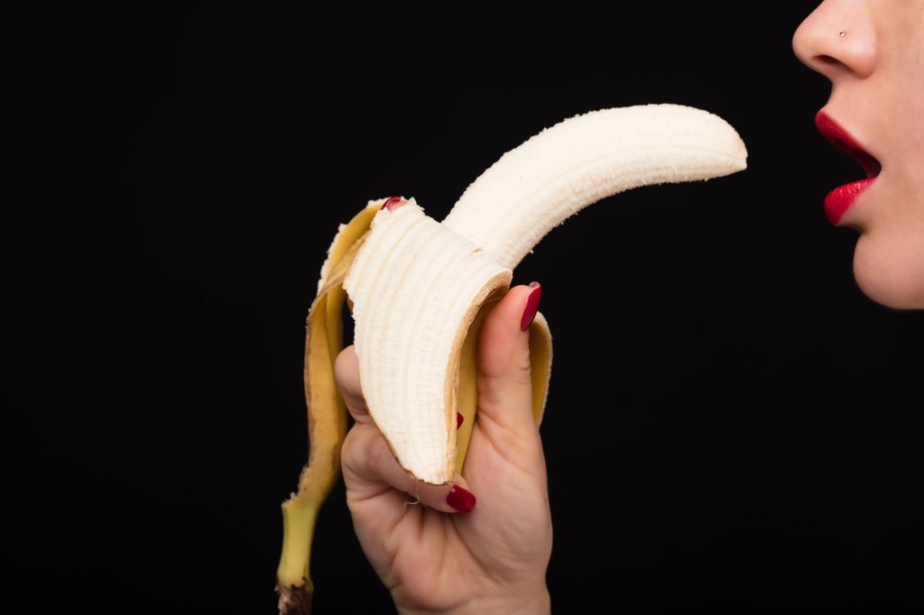 Foto de mulher segurando uma banana na frente da boca, em alusão ao sexo oral.