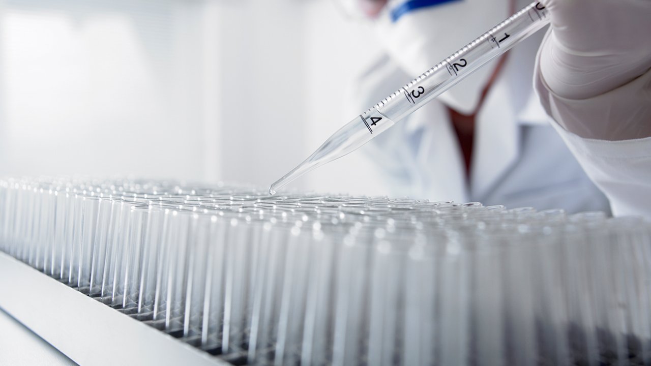 foto de cientista aplicando reagente em pipetas de laboratório