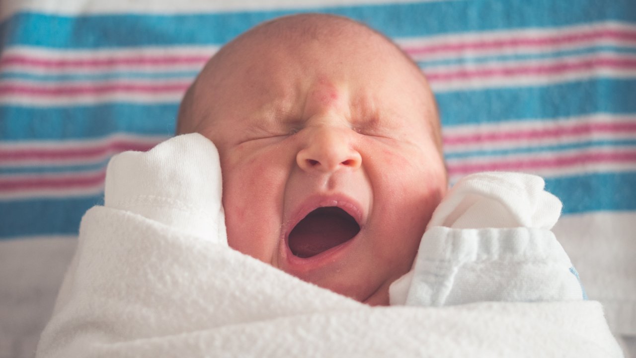 bebê bocejando, simbolizando sono de bebê que dorme de barriga para cima