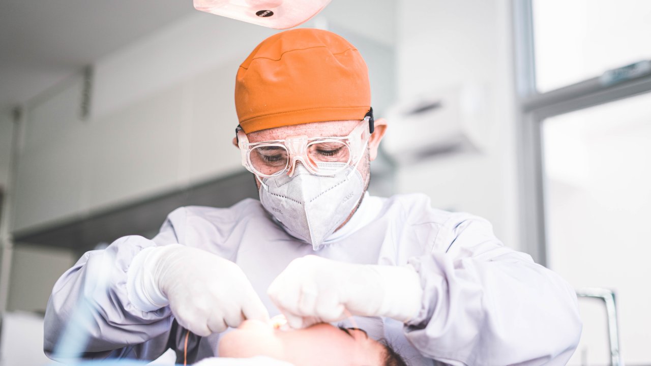 Foto de odontologista mexendo na boca de mulher em consultório